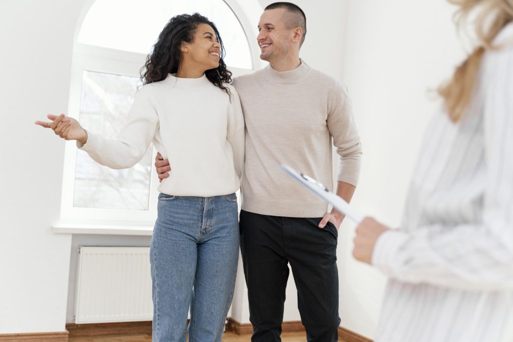 Jeune couple souriant dans leur nouvelle maison avec un agent Immobilier